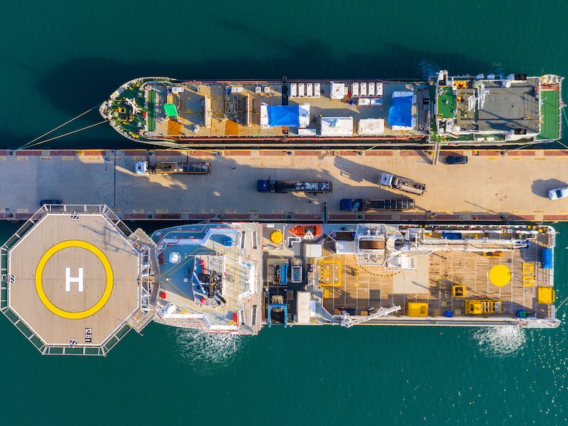 Offshore supply Ship docked next to a general Cargo vessel, Aerial image.